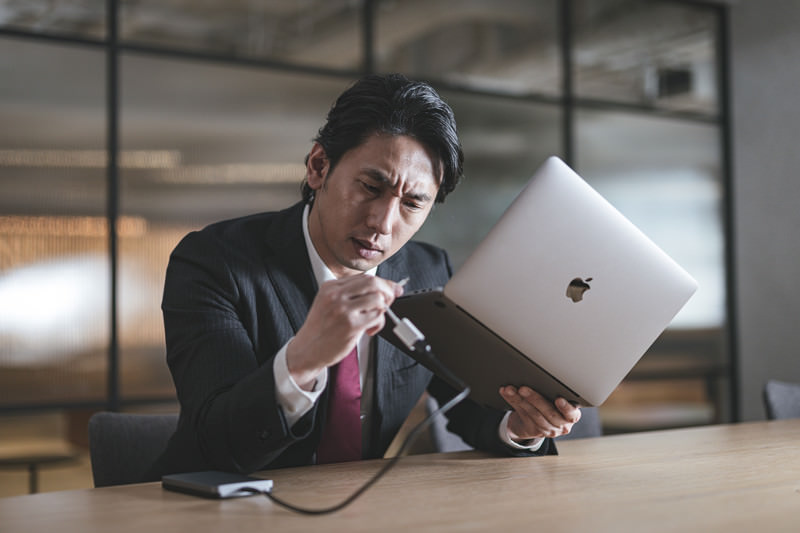 PCを持って、悩んでいる男性の画像